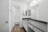 Bright and modern bathroom with sleek counter, large mirrors, and stylish wood flooring.