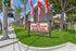 Inviting entrance to Westland @ Artesia in sunny Long Beach, CA, featuring vibrant red flags, lush palm trees, and a welcoming sign.