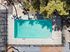 Inviting aerial view of a sparkling rectangular pool surrounded by a stylish patio and lush greenery.