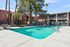 Inviting residential apartment complex featuring a sparkling pool area surrounded by lush trees and stylish balconies, perfect for relaxation and leisure.
