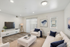 Bright and airy living room with modern decor, featuring plush white sofas, a sleek media console, and elegant lighting.