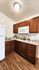 Cozy kitchen with rich wooden cabinets, sleek countertops, and modern appliances, featuring a stylish wooden floor.