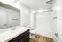 Bathroom with dark cabinets, white counters and hardwood floors