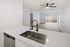 kitchen with sink, disherwasher, and countertops and view of living area with wooden floors and ceiling fan and patio