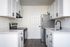 Newly renovated kitchen with white sharker cabinets, wood-inspired flooring, white hard-surface countertops, black fixtures and stainless steel appliances