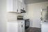 Newly renovated kitchen with white sharker cabinets, wood-inspired flooring, white hard-surface countertops, black fixtures and stainless steel appliances
