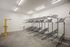 Pearl District, OR, Luxury Apartments for Rent - ORO - A Bike Storage Room with Concrete Flooring, Multiple Metal Bicycle Racks, and a Yellow Repair Stand.