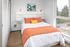 bedroom with vinyl wood like flooring and bed with orange accent pillows at aniva apartments