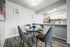 dining area with faux hardwood flooring and a round dining table with four gray chairs and the kitchen with breakfast bar behind at peoria grand apartments