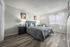 bedroom with faux hardwood flooring and two black bedside drawers and bed with grey cover at peoria grand apartments