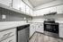 Updated kitchen with stainless steel dishwasher and stove/over with white cabinets and faux wood plank flooring