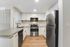 South Reno, NV, Apartments Near UNR - Redfield Ridge - Bright White Kitchen With Quartz Counters, Stainless Steel Refrigerator, Built-In Microwave, White Cabinets, and Light Wood Flooring.