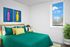 2-Bedroom Apartments in Woodstock, OR - Novus - A Bedroom with Decorative Pillows, a Bedside Table, A Lamp, Colorful Wall Art, and a Window.