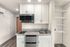 Studio Pointe Kitchen with white cabinets, stone countertops, stainless steel refrigerator and microwave, and 2 burner cooktop.