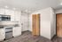 Studio Pointe Kitchen with white cabinets, stone countertops, stainless steel refrigerator and microwave, and 2 burner cooktop. Also includes built-in shelving