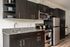Milano studio kitchen with stainless steel appliances and dark cabinets with wood-style plank flooring