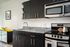 Milano studio kitchen with stainless steel appliances and dark cabinets with wood-style plank flooring