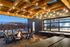 Bend, OR, Apartments With In-Unit Washer and Dryer - The Hixon - Rooftop Deck with Tile and Wood Plank Flooring, Fire Pit, Wood Chairs, a Large Table, a Long Counter with Seating, and String Lights.