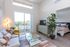 Studio Apartments in Bend, OR - The Hixon - Living Room with Wood-Style Flooring, a Couch, a Coffee Table, a TV on a Stand, Sliding Glass Doors to the Private Balcony, and a View into the Bedroom.