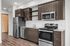 Studio kitchen with stainless-steel dishwasher, oven, range, microwave, and refrigerator, granite countertops and white subway-style backsplash.