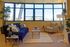 living room with large windows a blue sofa and a beige armchair and decorative plants around