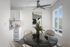 virtually staged kitchen with a ceiling fan and white cabinets and a round dining table with beige chairs