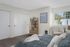 virtually staged bedroom with brown carpet sliding closet doors and bed with blue comforter and an arm chair at its corner
