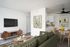 virtually staged living room with faux hardwood flooring and a green sofa with two coffee tables in front an entertainment console with a tv on the wall and a kitchen with a round dining table at boulder gardens