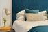teal bed headrest and comforter along with round table with a lamp