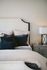 bed with blue accent pillows and grey side table with lamp