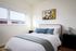1 Bedroom highrise Apartments in Portland OR - Jute - Furnished Bedroom with White Walls, Wood-Style Flooring, Twin Balck Nightstands, a Large Bed, and a WindowBedroom with ample natural light