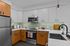 Staged kitchen with light green backsplash, stainless steel appliances, quartz countertops and dual tone wood and white cabinets