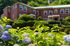 lush gardens and flowers with 2 story apartment building behind