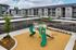 Pet-Friendly Apartments in Albany, OR - Creekside Meadows - Playground Featuring Green Slides and Safety Railings with Wood-Chip Ground, Surrounded by Carports and Building View.