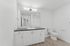 bathroom with wood-style flooring, white cabinets, and black countertops