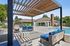 1-Bedroom Apartments in South Reno, NV - Redfield Ridge - Poolside Outdoor Lounge With Sofa Seating, Hanging Chair, Coffee Table, and Wooden Pergola Beside The Community Pool.