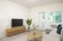 Tigard, OR, Apartments Near Bridgeport Village - Pacific Ridge Apartments - Living Area with Wood-Style Flooring, Couch, Nested Coffee Tables, Media Console, and Flat TV.