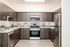 Tigard, OR, Apartments Near Washington Square Mall - Pacific Ridge Apartments - Kitchen with Custom Cabinetry, Energy-Efficient Stainless Steel Appliances, Wood-Style Flooring, and Light Fixture.