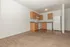 carpeted dining area and kitchen with white appliances and wood like flooring