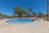 pool with chairs and tables around and palm trees in the background