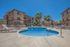 pool with lounge chairs and three story apartment buildings in the back
