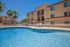pool with lounge chairs and 3 story apartment building in the background