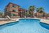 pool with lounge chairs and three story apartment buildings in the back