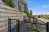 Dog-Friendly Apartments in Tigard, OR - Pacific Ridge Apartments - A Dog Run with a Retaining Wall, Sloped Ground, and Enclosed in a Black Metal Fence.