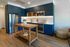 Kitchen fully staged with blue custom cabinetry and stainless steel appliancees