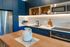 Kitchen fully staged with blue custom cabinetry and stainless steel appliancees