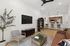 Pet-Friendly Luxury Apartments In Midtown Phoenix, AZ - Asa Midtown - Living Room with a Dark Sectional Couch, Armchairs, Glass Coffee Table, Wall-Mounted TV, and a Cowboy Artwork.
