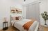 One-Bedroom Luxury Apartments in Midtown Phoenix, AZ - Asa Midtown - A Bedroom with a Queen-Size Bed, Desert-Inspired Artwork, Sleek Nightstands, a Sliding Barn-Style Door, and a Hanging Potted Plant.