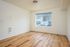 Ground floor bedroom with wooden floor and window showing parking lot.