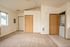 Main living space showing entrance, bedroom door, and laundry with carpet and kitchen tiles.